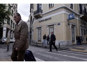 People walk past an Alpha bank branch in central Athens on January  29, 2015. Economic powerhouses Germany and China warned Greece on January 29 against reneging on reforms tied to its massive international bailout, with markets still jittery over fears Athens could default on its debt.