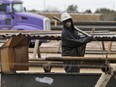 A worker caries oil well piping in Sweetwater, Tex., Dec. 23, 2014.