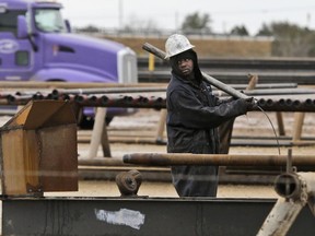 A worker caries oil well piping in Sweetwater, Tex., Dec. 23, 2014.