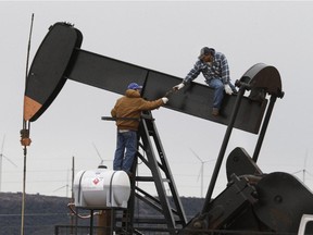 Men work on an oil-well pump near  Sweetwater, Texas in December 2014.