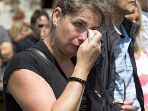 A mourner wipes away tears outside the Ste-Agnès church in Lc-Mégantic, Sunday, July , 2014, during a mass to mark the first anniversary of the train  disaster that left 47 people dead and levelled the centre of the community.
