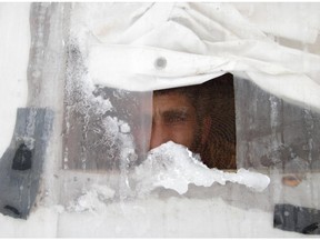 A Syrian refugee looks out of a gauze window of his tent at a refugee camp in the eastern Lebanese town of Arsal in the Bekaa valley, near the border with Syria, on January 7, 2015 as a heavy stow storm hit the region. Many Syrian refugees  were trapped in their tents by the heavy rain and snow, struggling to stay warm in temperatures hovering around zero degrees.