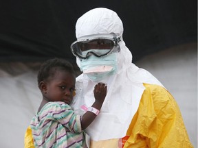 A Doctors Without Borders (MSF) health worker in protective clothing holds a Liberian child suspected of having Ebola in 2014.