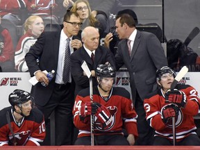 New Jersey Devils defensive coach Scott Stevens, left, and offensive coach Adam Oates, right, confer with general manager Lou Lamoriello behind bench during game against the Pittsburgh Penguins on Dec. 29, 2014, in Newark, N.J.