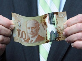 The new polymer-based $100 bill  (Finance Minister Jim Flaherty holds a new polymer-based $100 bill as he takes part in the unveiling of the new polymer bank notes in $50 and $100 denominations at the Bank of Canada in Ottawa on Monday, June 20, 2011. The penny may be history, but some Canadians suspect the Bank of Canada has been circulating a new scent along with its plastic bank notes. Dozens of people who contacted the bank in the months after the polymer notes first appeared asked about a secret scratch-and-sniff patch that apparently smells like maple syrup.THE CANADIAN PRESS/Sean Kilpatrick ORG XMIT: CPT102)  Possible art for Kirsten Smith (Postmedia News) 0912-nhs-highlights & 0912-nhs-income-box: ORG XMIT: POS1305261119572133