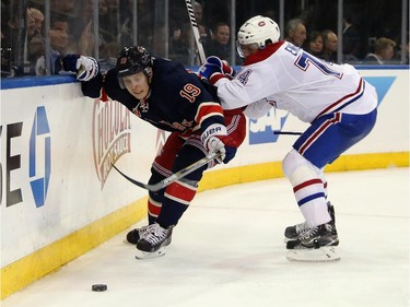 Jesper Fast (#19) of the New York Rangers is checked by Alexei Emelin (#74) of the Montreal Canadiens during the second period at Madison Square Garden on January 29, 2015 in New York City.
