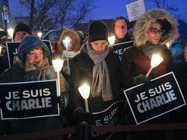 Chantal Pelosse, Wilfred Savoy, middle and Jeremy Dupont, right, were among the supporters who  braved the cold during a vigil organized by Montreal City Hall on Wednesday night in support of the victims of the terrorist attack in Paris. Banners saying Je suis Charlie were held by supporters in memory of Charlie Hebdo's victims.