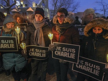 Chantal Pelosse, left, Wilfred Savoy, Jemery Dupont and Justine Janvier hold candles and signs during vigil in support of the victims of the Charlie Hebdo terrorist attack in Paris, outside City Hall in Montreal, Wednesday January 7, 2015.