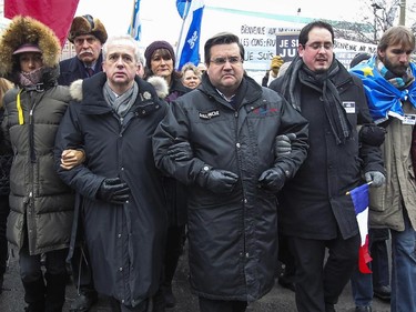 Mayor Denis Coderre, third from right, links arms with French consul general Bruno Clerc, to his right, as they lead a silent march through the streets of Montreal Sunday January 11, 2015 in support of the victims of terrorist attacks in France last week.