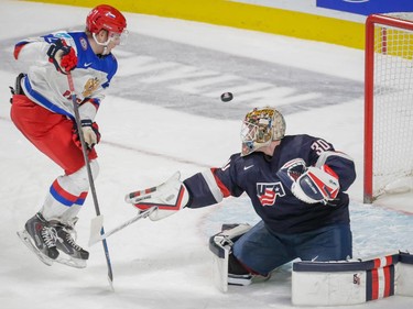 Team Russia forward Ivan Barbashyov, jumps out of the way of a shot as it flies past Team USA goalie Thatcher Demko, right, during the second period of their 2015 IIHF World Junior Championship quarterfinal match .