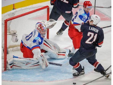 Team USA forward Dylan Larkin, right, attempts a shot against Team Russia forward Alexander Sharov, centre, and goalie Igor Shestyorkin, left, during the second period of their 2015 IIHF World Junior Championship quarterfinal match