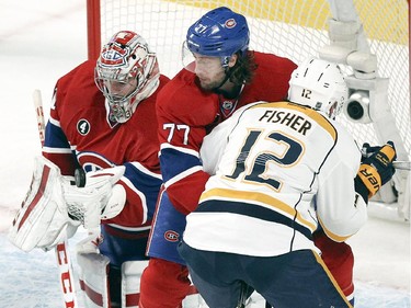 Montreal Canadiens goalie Carey Price juggles the puck as teammate Tom Gilbert holds off Nashville Predators Mike Fisher during first period of National Hockey League game in Montreal Tuesday January 20, 2015.