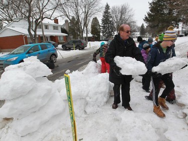 Beaconsfield Mayor Georges Bourelle  carries a piece of snow from the road in front of Yann Lefebvre's house.