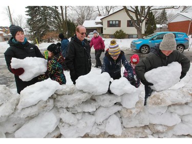 Beaconsfield Mayor Georges Bourelle (wearing glasses) watches a new wall of snow being built further back from the road.