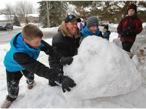 Yann Lefebvre, with the help of neighbourhood children, rolls a piece of a snow fort up a hill away from the road in front of his house in the Beaconsfield area of Montreal, on Saturday, January 24, 2015.   Lefebvre was hosting a "moving party" to move the snow fort to another area of his lot. Early in the new year, Lefebvre built a snow fort in his front yard for his and other children to enjoy, but it wasn't long before he was contacted by the city and told to take it down. Mayor Georges Bourelle says the fort encroached on city property and poses a risk to both children and city workers.