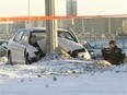 A Montreal police officer photographs a car that went off the road when the dirver lost control, on the Highway 40 W service road in Pointe Claire Jan. 26, 2015.