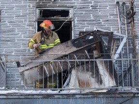 A Montreal firefighter looks through debris as he investigates the cause of a fire at a rooming house on St-Urbain St. Jan. 28, 2015.