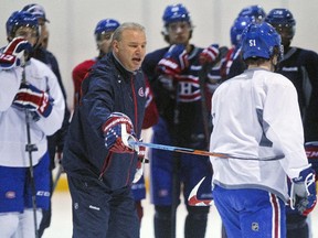 Canadiens coach Michel Therrien hooks a stick around David Desharnais  during practice at the team's training facility in Brossard on Jan.  28, 2015.