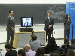 Parti Québécois leadership candidate Pierre Karl Péladeau, on screen remotely from Baie-Comeau, speaks during a leadership debate at the Université de Montréal in Montreal, Wednesday January 28, 2015. It was the first debate of the party's leadership race to replace former leader and premier, Pauline Marois. The other candidates are Alexandre Cloutier (left), Bernard Drainville and Martine Ouellet (right) and, labour activist Pierre Céré (not shown).