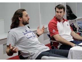 Montreal Alouettes running backs coach Ryan Dinwiddie (right) listens to quarterback Jonathan Crompton at a luncheon where the coaching staff hosted the media in the locker room at the Olympic stadium in Montreal Thursday, January 29, 2015. The team finished with a 9-9 record in 2014.
