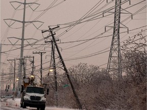 Hydro crews wait for back up to replace a damaged hydro pole on Champlain boulevard in Montreal on Sunday January 4, 2015. Police said the crews are worried in the pole falls completely, it would cause a chain reaction and and take several other poles down with it.