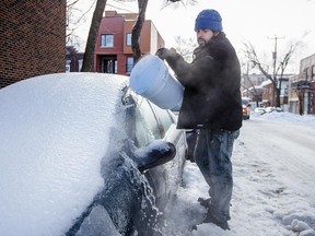 Morgan Pruneta uses hot water to remove ice from his car on Gounod street in Montreal on Monday, January 5, 2015. Montreal and parts of Quebec were hit by an ice storm on Sunday, January 4, 2015.