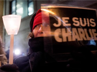 A woman holds a candle and a Je Suis Charlie sign as she participates in a candle light vigil outside the French Consulate in Montreal on Wednesday January 7, 2015. Montrealers gathered in support of the victims of the terrorist attack on Charlie Hebdo in Paris earlier today that left 12 people dead and 11 injured.