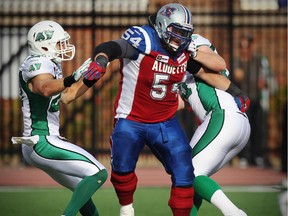 Alouettes offensive lineman Jeff Perrett takes on two Saskatchewan Roughriders during CFL game at Montreal's Molson Stadium on Oct. 13, 2014.
