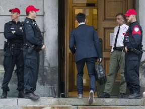 Montreal police and a security keep an eye on people entering Montreal city hall, Wednesday, October 29, 2014.  In the wake of the Ottawa shooting, there was an increased police presence at city hall.