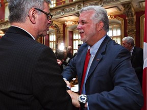 Quebec Premier Philippe Couillard shakes hands with Jean-Marc Fournier as he arrives at a party caucus meeting at the Quebec legislature, Monday, Jan.26, 2015