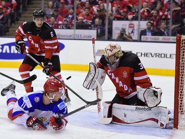 Russia's Nikolai Goldobin watches the puck as he slides in front of Canada's goalie Zachary Fucale during first period gold medal game hockey action at the IIHF World Junior Championship in Toronto on Monday, Jan. 5, 2015. Canada's Sea Theodore is in background.