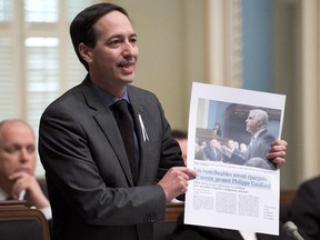 Quebec Opposition Leader Stephane Bédard holds a copy of a Montreal newspaper while criticizing the government, Dec. 4, 2014.