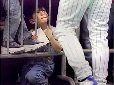 Five year old Kim Phan looks up at Montreal Expos pitcher Pedro Martinez signing autographs during Kids' Day at the Olympic Stadium April 5, 1997. The Expos lost 15-3 to the Colorado Rockies.