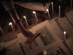 A woman lays pencils on top of messages and around flowers and candles displayed outside the Cultural and Art centre in Bangkok on January 8, 2014, in tribute to the twelve people killed the day before in an attack by two armed gunmen on the offices of French satirical newspaper Charlie Hebdo in Paris. The massacre, the country's bloodiest attack in half a century, triggered poignant and spontaneous demonstrations of solidarity around the world. Charlie Hebdo is famed for its irreverent views of religion and its decision to publish controversial cartoons of the prophet Mohammed.