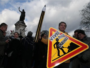 TOPSHOTS A man holds a replica pencil and a sign that reads, "All live together" at the Place de la Republique at the start of a Unity rally Marche Republicaine on January 11, 2015 in Paris in tribute to the 17 victims of a three-day killing spree by homegrown Islamists. The killings began on January 7 with an assault on the Charlie Hebdo satirical magazine in Paris that saw two brothers massacre 12 people including some of the country's best-known cartoonists, the killing of a policewoman and the storming of a Jewish supermarket on the eastern fringes of the capital which killed 4 local residents.