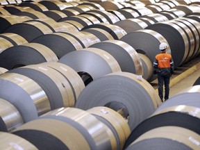 An employee looks at coils of steel treated by galvanization and stored in ArcelorMittal's "cold factory" in France.