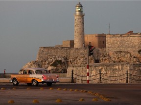 With the Castillo San Felipe del Morro standing in the background, an old American car drives along the Paseo del Prado in the Habana Vieja neighborhood January 21, 2015 in Havana, Cuba.