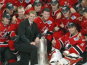 Team Canada executive director Wayne Gretzky, Mario Lemieux, centre, goalie Martin Brodeur, right, and the rest of the team surround the World Cup trophy for a photo after defeating Finland 3-2 in Toronto on  Sept. 14, 2004, the last time the tournament was held.