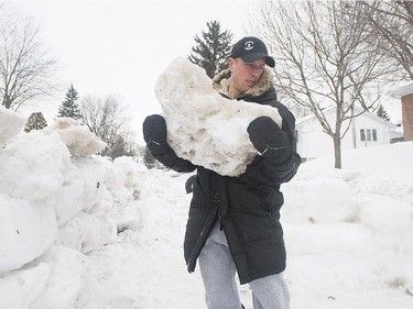 Yann Lefebvre removes an ice block from his snow fort at his home.