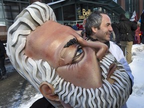 A protester walks away with the head of Quebec Premier Philippe Couillard during a demonstration against the Quebec government's austerity measures, Feb. 23, 2015 in Montreal.