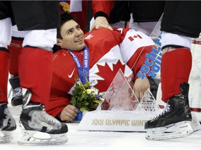 Team Canada goalie Carey Price lies on the ice with his team's trophy after beating Sweden 3-0 in the gold- medal game at the 2014 Winter Olympics on Feb. 23, 2014, in Sochi, Russia.