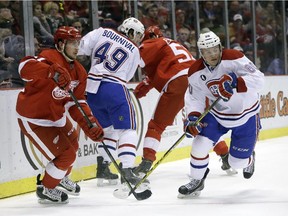 Detroit Red Wings left wing Tomas Tatar (21), of the Czech Republic, and Montreal Canadiens right wing Christian Thomas (60) chase the puck during the first period of an NHL hockey game Monday, Feb. 16, 2015, in Detroit.