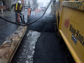Construction crews from Simard Beaudry lay fresh asphalt down on top of slush, snow, leaves and garbage as they rush to resurface St. Laurent St. as part of the street's revamping in November 2007.