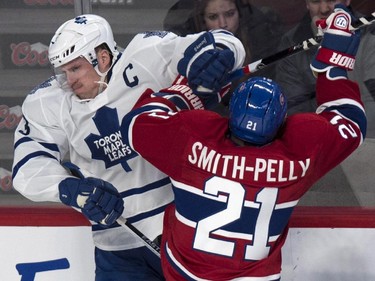 Toronto Maple Leafs' Dion Phaneuf is checked into the boars by Montreal Canadiens' Devante Smith-Pelly during first period NHL hockey action Saturday, February 28, 2015 in Montreal.