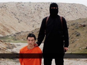 GRAPHIC CONTENT - This image made from a video released by Islamic State militants on Saturday, Jan. 31, 2015, purports to show a militant standing next to Japanese journalist Kenji Goto before his beheading by the militant group. Goto was captured in October 2014, after he traveled to Syria to try to win the release of Haruna Yukawa.