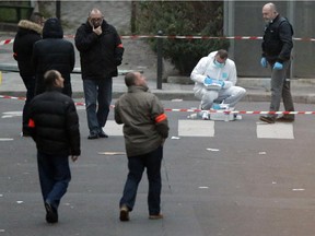 French forensic experts and police officers examine evidence outside the office of French satirical newspaper Charlie Hebdo in Paris, Wednesday, Jan. 7, 2015. Three masked gunmen stormed the Paris offices of the newspaper on Wednesday, killing 12 people, including its editor, before escaping in a car. It was France's deadliest postwar terrorist attack.