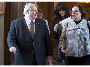 Quebec Health Minister Gaetan Barrette, left, and Minister for Rehabilitation, Youth Protection and Public Health Lucie Charlebois, right, walk to a party caucus as the National Assembly reconvenes to pass a special legislation on health Friday, February 6, 2015 at the legislature in Quebec City.