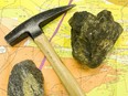 Iconic image of survey map, geologist's hammer, loupe or hand glass and rock containing real and fool's gold.
