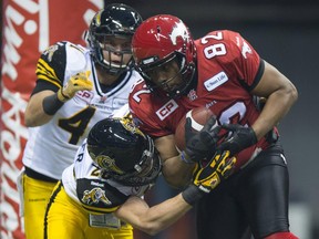 Hamilton Tiger-Cats defensive-backs Erik Harris (41) and Craig Butler try to stop Calgary Stampeders slotback Nik Lewis during the 102nd Grey Cup in Vancouver on Nov. 30, 2014.