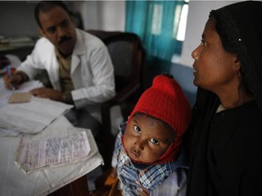 In this Saturday, Feb. 1, 2014 photo, a doctor attends to Anwar, 4, infected with tuberculosis at the Kashi Vidyapith block hospital in Kotawa near Varanasi, India.